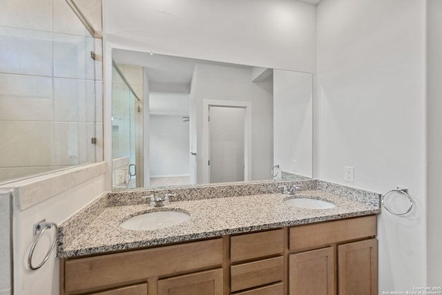 bathroom with double vanity, a shower stall, and a sink