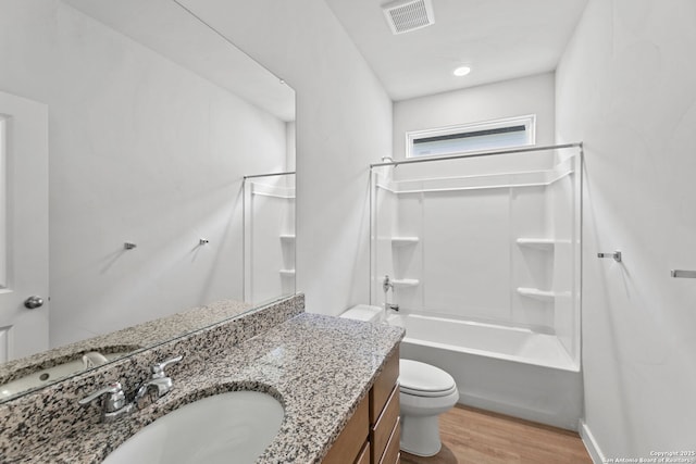 bathroom featuring visible vents, toilet, wood finished floors, vanity, and shower / bathtub combination