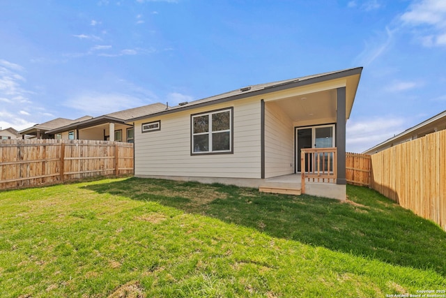 rear view of house with a patio area, a fenced backyard, and a yard