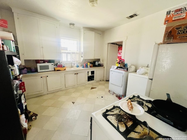 kitchen featuring white microwave, visible vents, light floors, white cabinetry, and separate washer and dryer