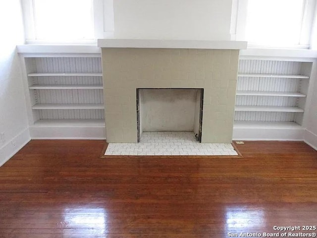 interior details featuring a fireplace with flush hearth, wood finished floors, and baseboards