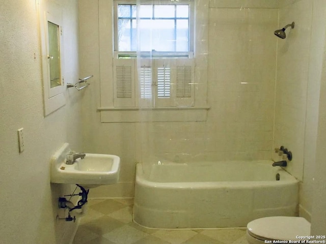 bathroom featuring toilet, tub / shower combination, and a sink