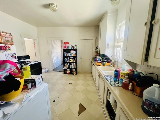 kitchen with gas range oven, freestanding refrigerator, white cabinets, light countertops, and light floors