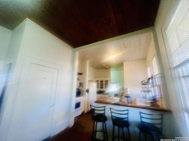 kitchen featuring white gas stove, a kitchen breakfast bar, and wooden ceiling