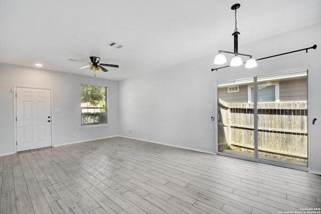 interior space with wood finished floors, a ceiling fan, and baseboards