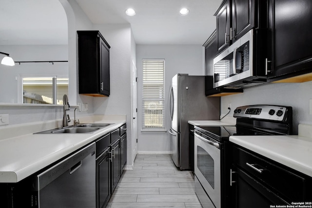 kitchen featuring light countertops, dark cabinets, appliances with stainless steel finishes, and a sink