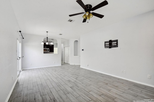 unfurnished living room featuring visible vents, baseboards, ceiling fan, and wood finished floors