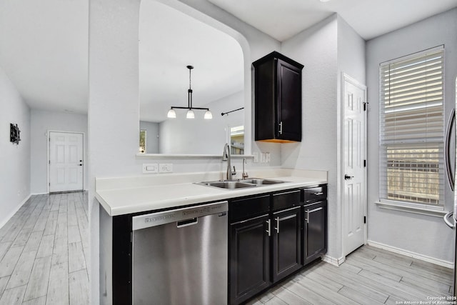 kitchen featuring a sink, dishwasher, wood tiled floor, and light countertops