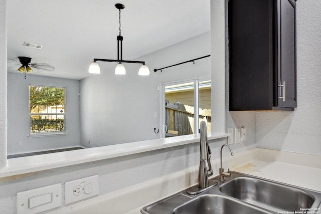 interior space featuring visible vents, a sink, decorative light fixtures, light countertops, and ceiling fan