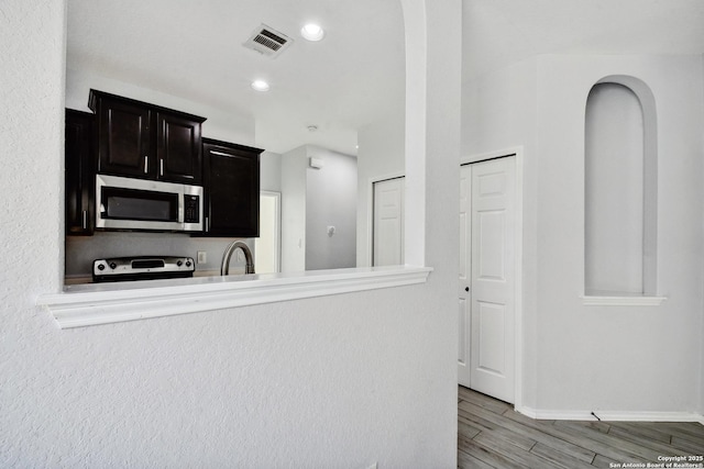 kitchen featuring visible vents, light wood-style flooring, a sink, stove, and stainless steel microwave