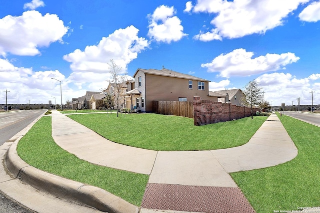 view of property's community with a residential view, a lawn, and fence