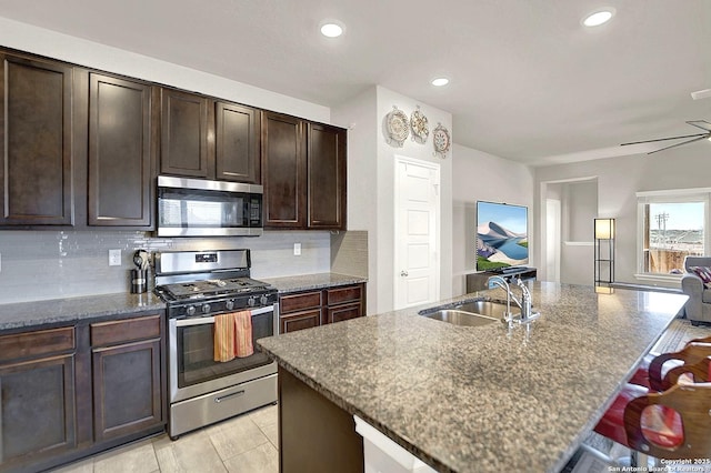 kitchen with a sink, stainless steel appliances, tasteful backsplash, and dark stone counters