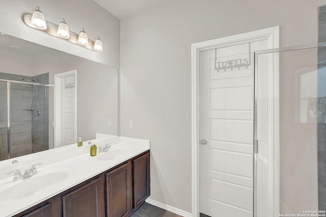 full bath featuring a shower stall, double vanity, and a sink