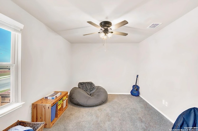 living area featuring carpet, a ceiling fan, visible vents, and baseboards