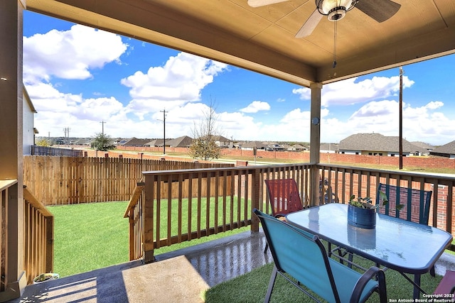 wooden terrace featuring a lawn, fence, a residential view, and ceiling fan