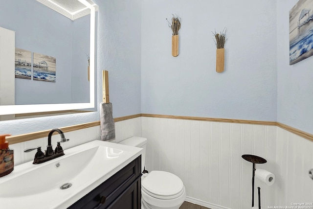 bathroom featuring vanity, toilet, and wainscoting