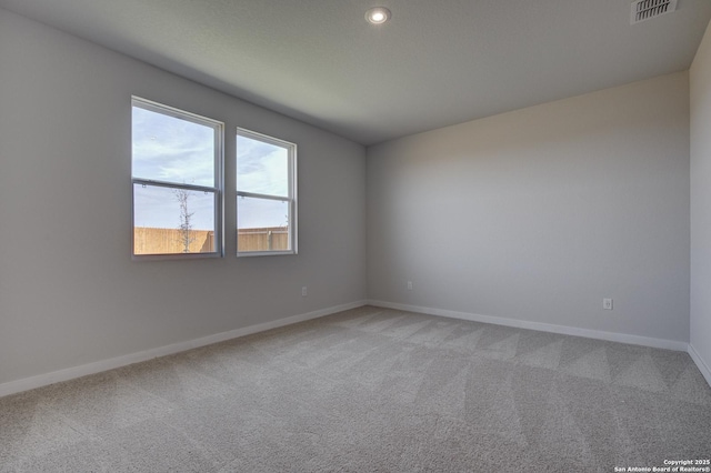 spare room with visible vents, light colored carpet, and baseboards