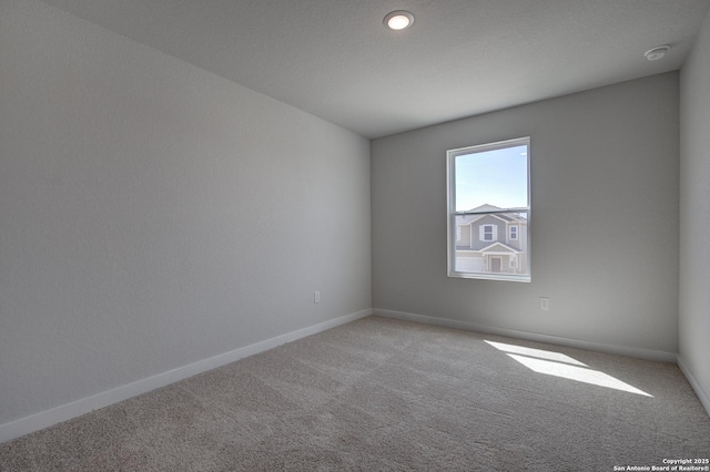 carpeted spare room featuring baseboards