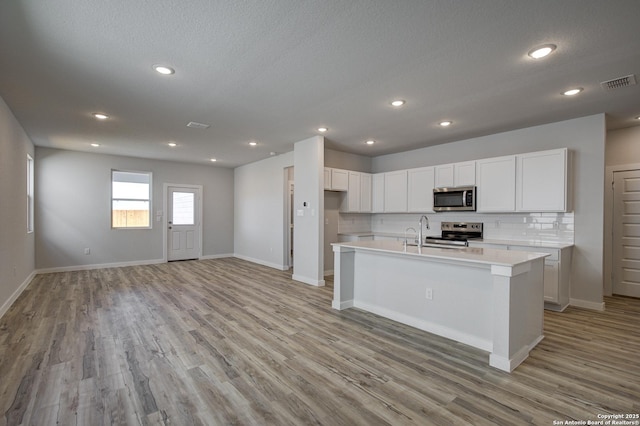 kitchen with visible vents, decorative backsplash, light countertops, white cabinets, and appliances with stainless steel finishes