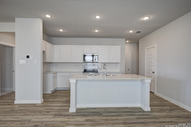 kitchen with a sink, stainless steel appliances, visible vents, and wood finished floors