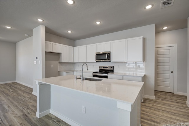 kitchen with a sink, visible vents, appliances with stainless steel finishes, and white cabinetry