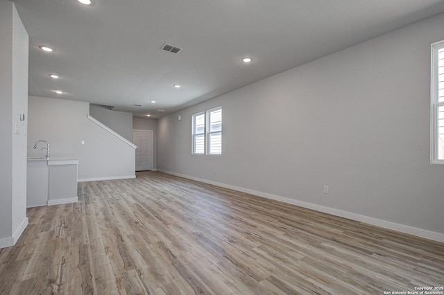 unfurnished living room featuring baseboards, visible vents, light wood finished floors, recessed lighting, and a sink