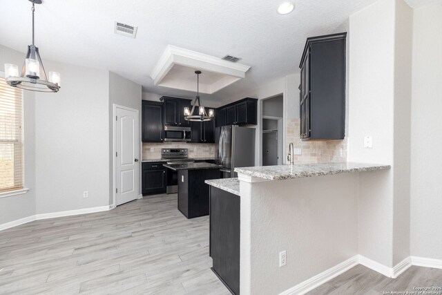 kitchen with visible vents, an inviting chandelier, stainless steel appliances, a raised ceiling, and tasteful backsplash