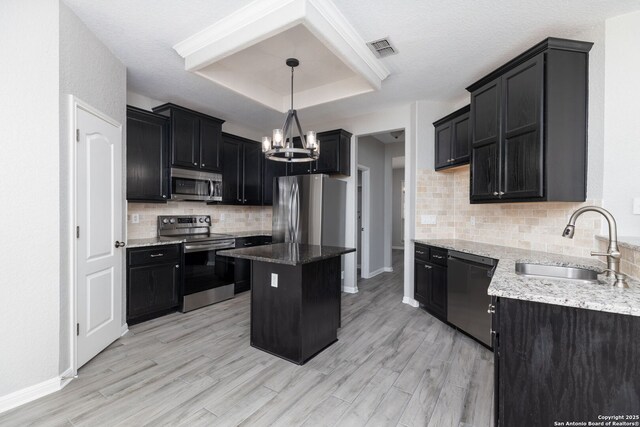 kitchen featuring visible vents, a sink, a tray ceiling, stainless steel appliances, and dark cabinets