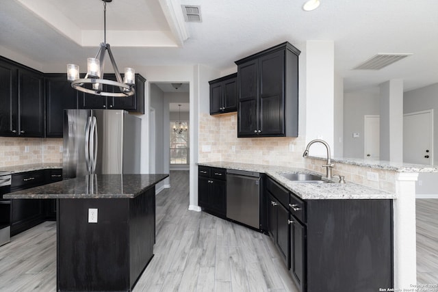 kitchen with visible vents, a tray ceiling, appliances with stainless steel finishes, an inviting chandelier, and a sink
