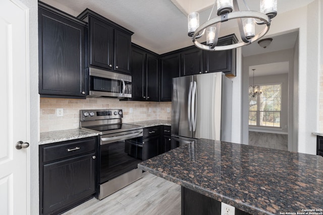 kitchen featuring stainless steel appliances, a notable chandelier, and dark cabinets
