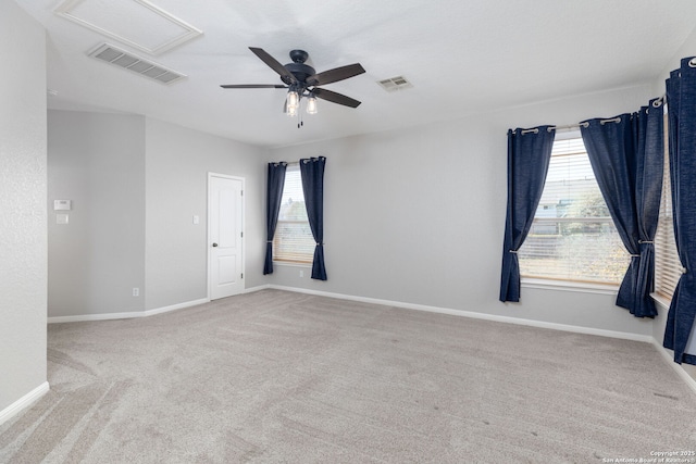 carpeted spare room featuring a wealth of natural light, visible vents, and a ceiling fan
