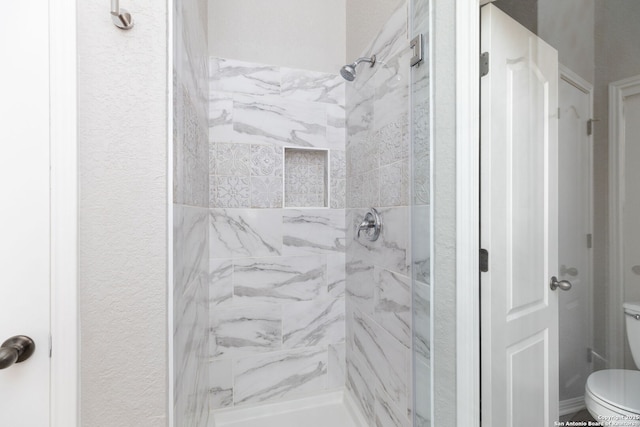 bathroom with a shower stall and toilet