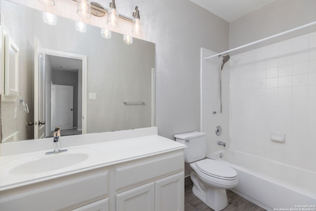 full bath with toilet, wood finished floors, shower / bath combination, vanity, and a textured wall