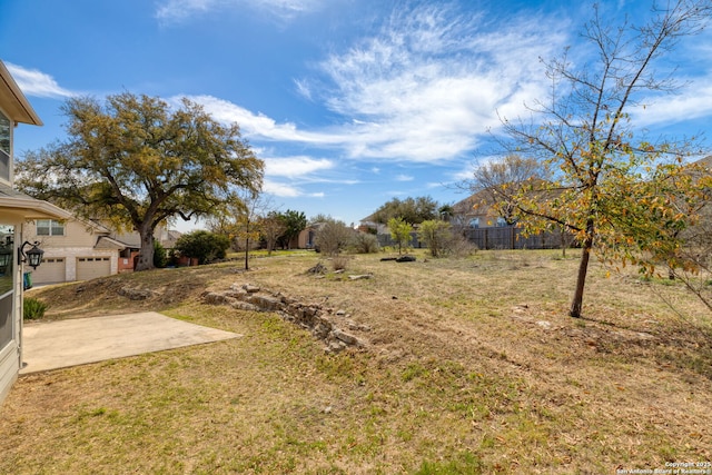 view of yard with driveway, a garage, and fence