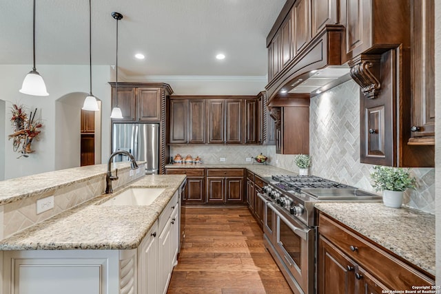 kitchen with dark wood-type flooring, a sink, tasteful backsplash, stainless steel appliances, and hanging light fixtures