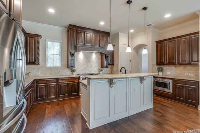 kitchen with dark wood-style floors, visible vents, appliances with stainless steel finishes, crown molding, and a kitchen breakfast bar