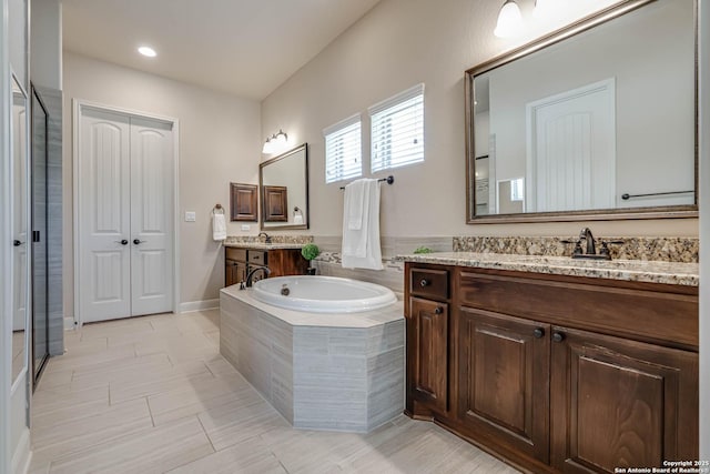 full bathroom featuring two vanities, a bath, and a sink