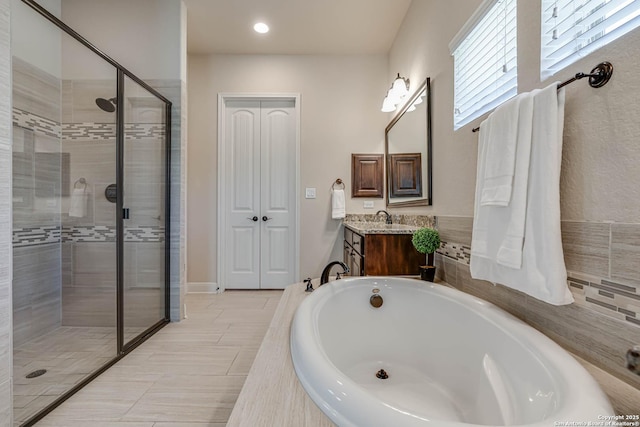 bathroom featuring a garden tub, a stall shower, and vanity