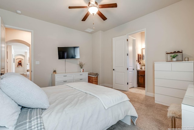 bedroom with visible vents, ceiling fan, light carpet, ensuite bathroom, and arched walkways