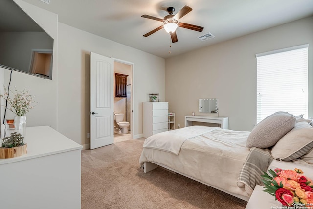 bedroom with visible vents, connected bathroom, baseboards, light colored carpet, and a ceiling fan