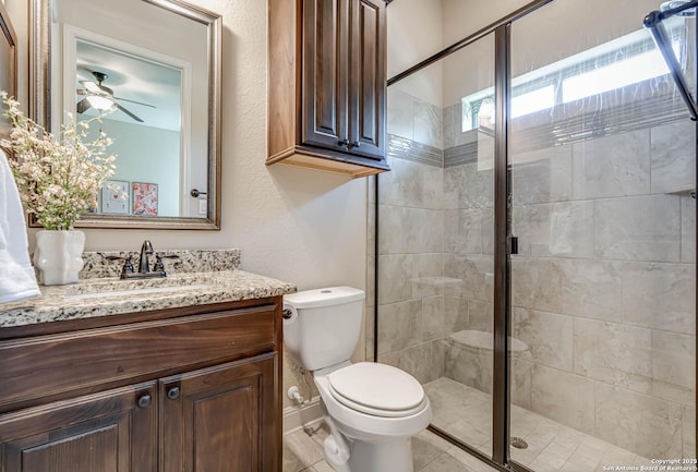 bathroom with a shower stall, toilet, vanity, and ceiling fan