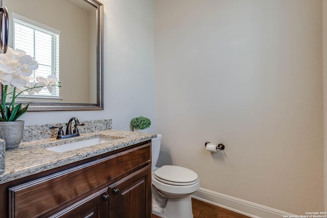 bathroom featuring toilet, vanity, and baseboards