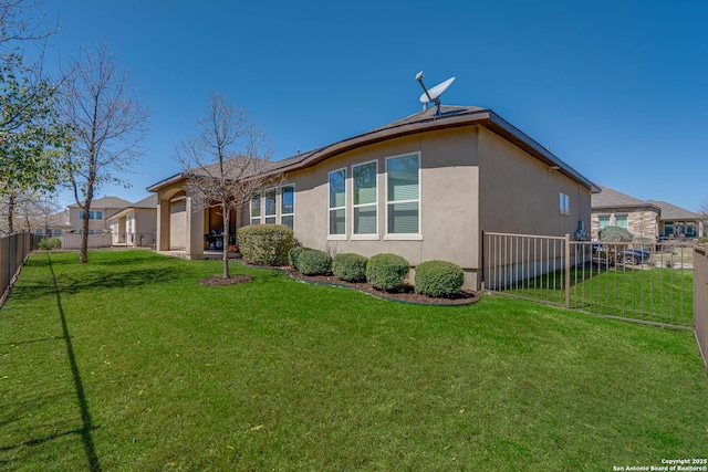 rear view of house with a yard, fence, a garage, and stucco siding