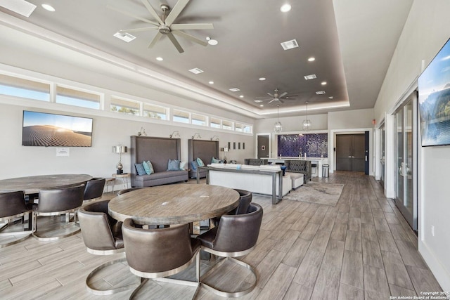 dining area featuring visible vents, a raised ceiling, ceiling fan, and wood tiled floor