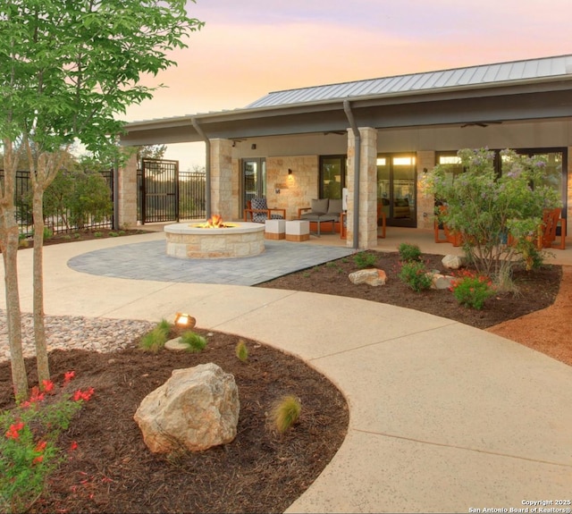 exterior space with stone siding, an outdoor living space with a fire pit, a patio, and metal roof