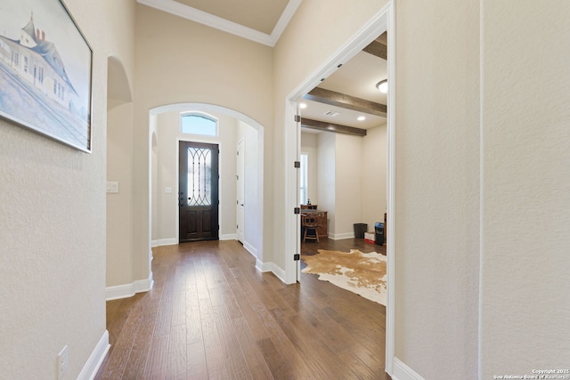 foyer entrance featuring arched walkways, ornamental molding, baseboards, and hardwood / wood-style flooring