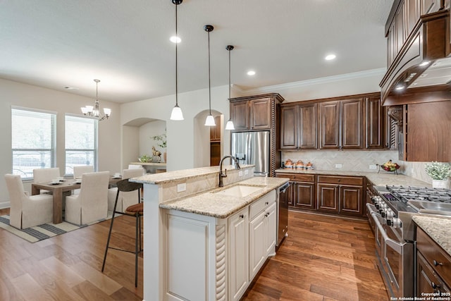 kitchen featuring dark wood-type flooring, arched walkways, custom exhaust hood, stainless steel appliances, and a sink