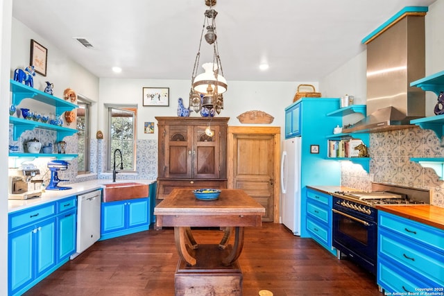 kitchen featuring blue cabinets, open shelves, a sink, white appliances, and wall chimney exhaust hood