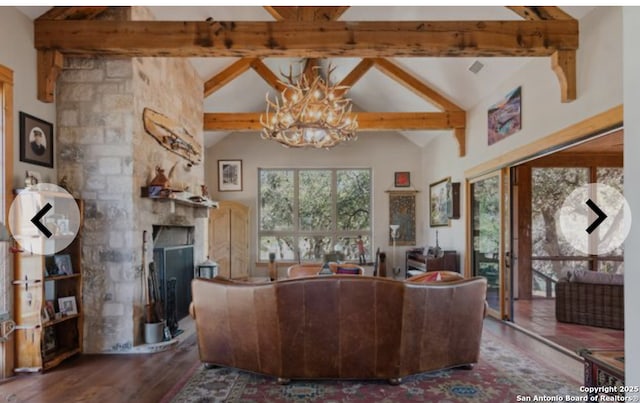 living area with a notable chandelier, vaulted ceiling with beams, a stone fireplace, and wood finished floors