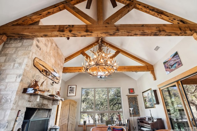 unfurnished dining area with beamed ceiling, ceiling fan with notable chandelier, a large fireplace, and visible vents